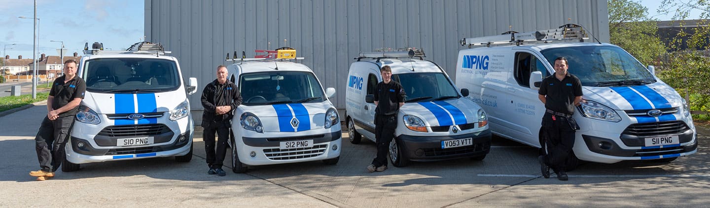 Four men in black uniforms stand in front of four white service vans with blue stripes, parked side by side on a concrete drive near a metal building.