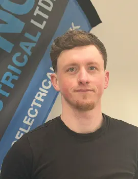 A young man in a black crew-neck shirt stands in front of a blue and black company banner.